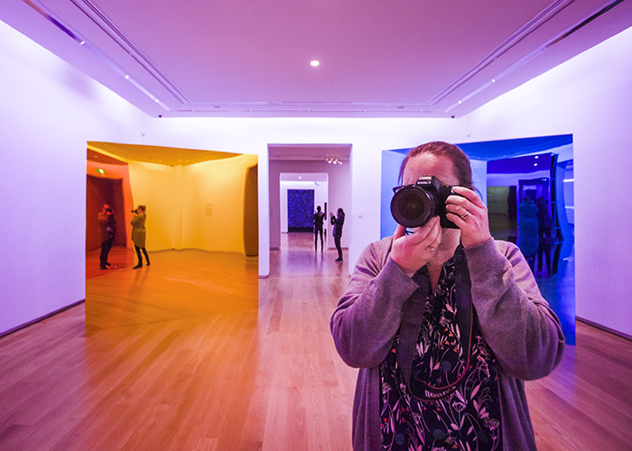 A photographer points the camera towards the camera in an art gallery setting - using color in photography